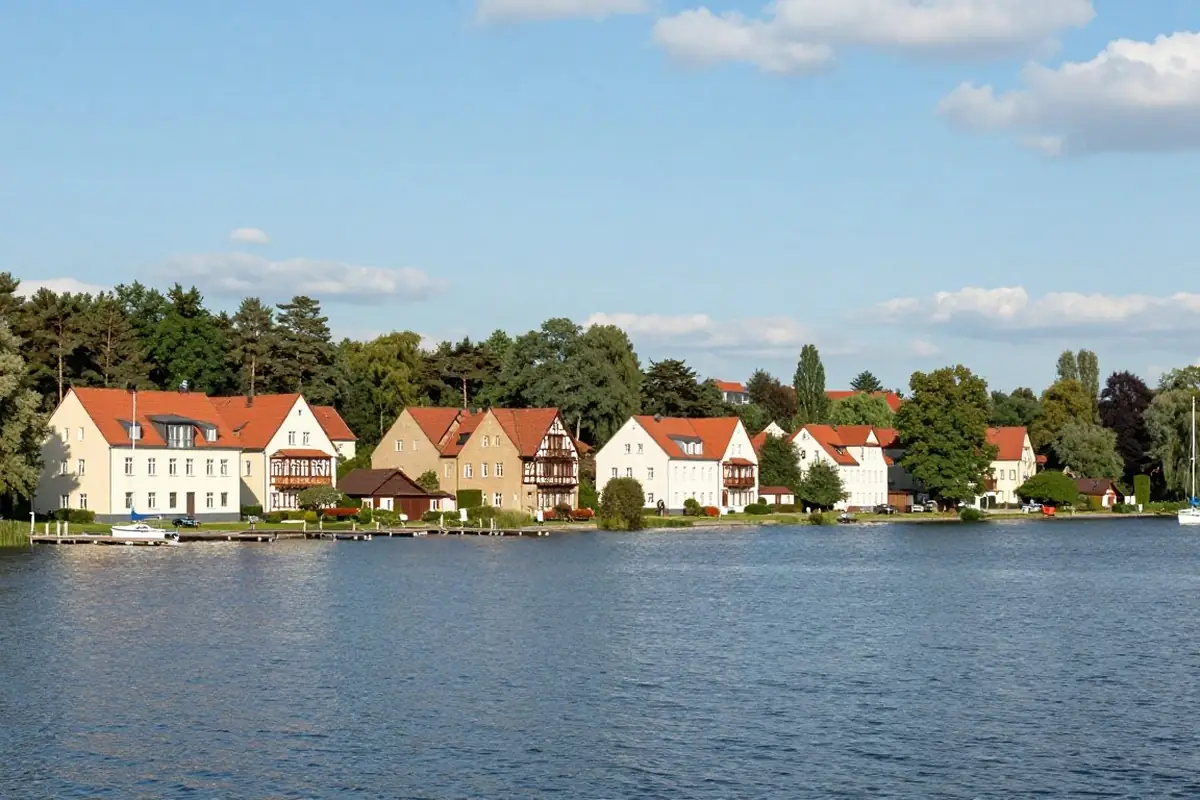 Großer See mit Segelbooten und Villen am Ufer